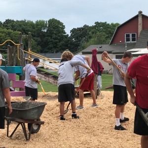 The St. John Fisher College football players spread mulch on the playground as part of their Day of 